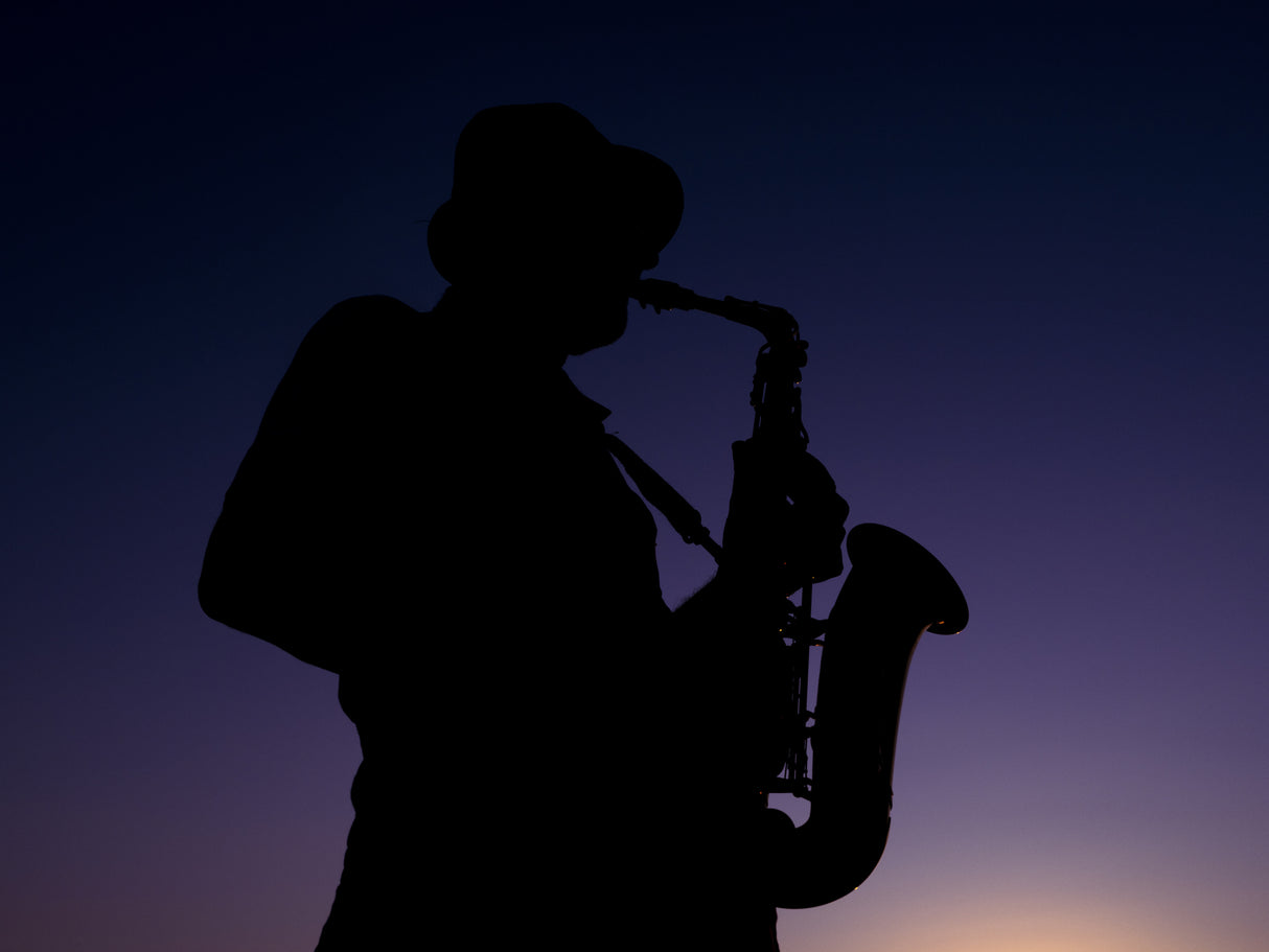 a musician playing the saxophone at sunset Poster och Canvastavla