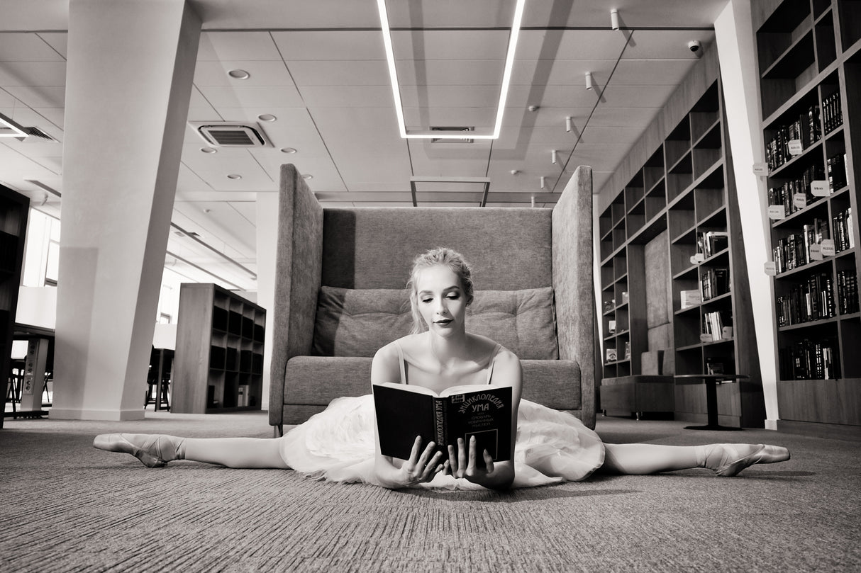 the Dreamer. ballerina on pointe shoes in the library reads a book holding it up Poster och Canvastavla