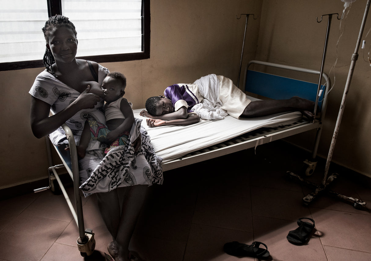 A grandmother breastfeeds her grandson while visiting her sick daughter - Ghana Poster och Canvastavla