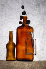Still life with colored bottles and a dried twig Poster och Canvastavla