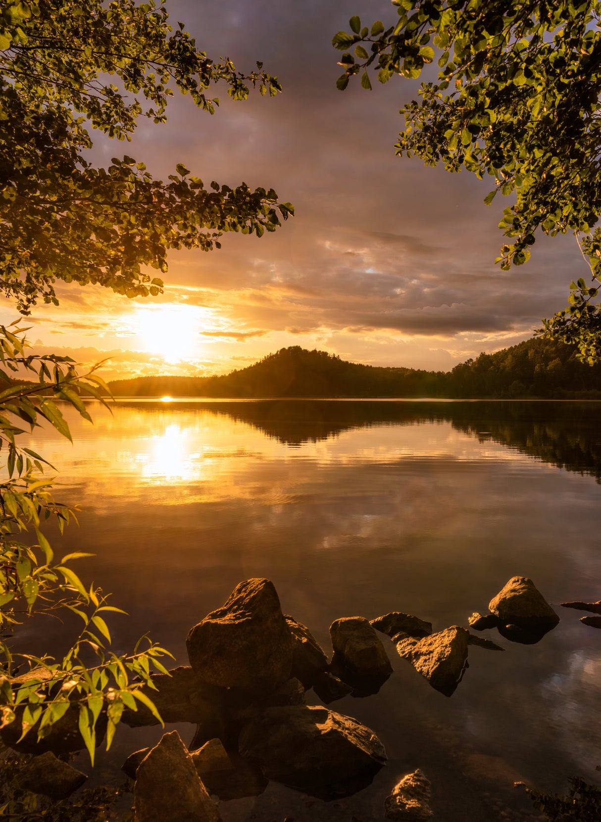 Sunset at a lake with a small mountain in the background Poster och Canvastavla