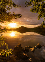 Sunset at a lake with a small mountain in the background Poster och Canvastavla