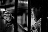 A young monk behind the bars of a Buddhist school Poster och Canvastavla