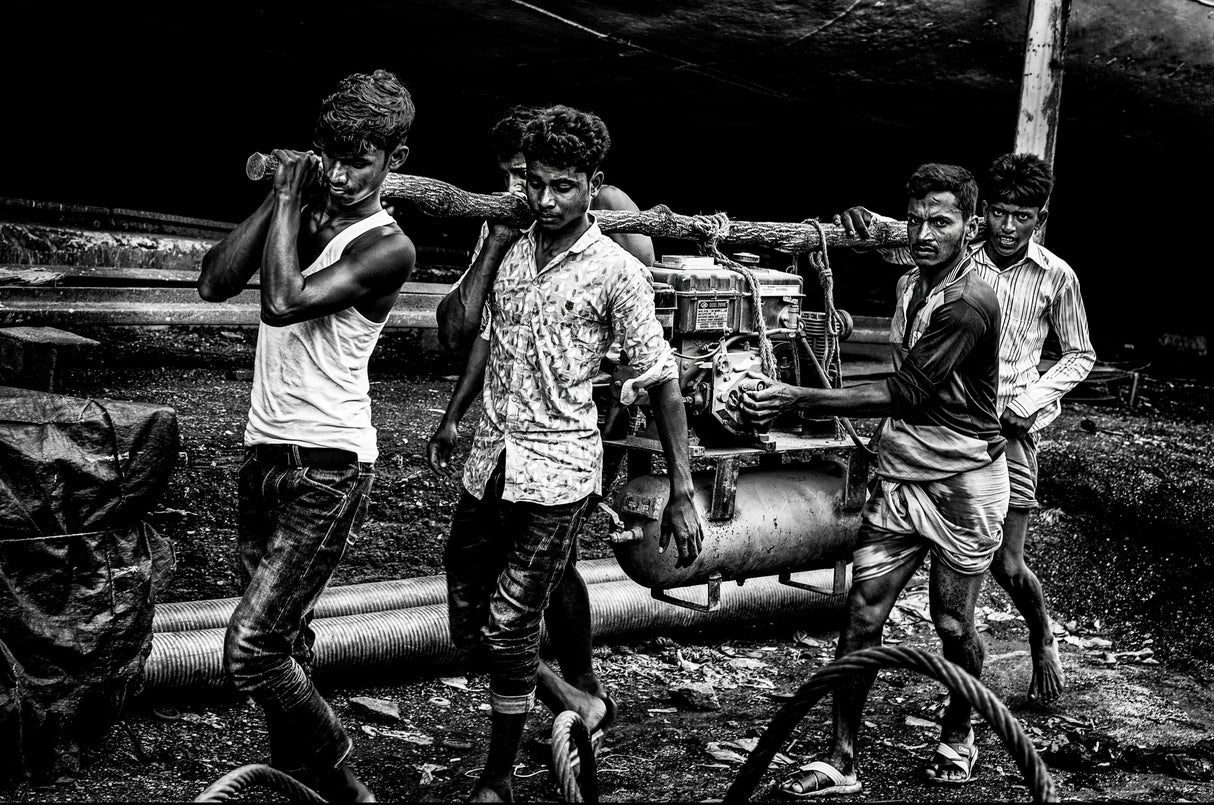 Carrying a motor in a shipyard in Bangladesh. Poster och Canvastavla